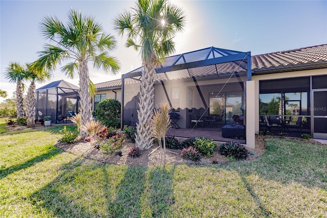 back of property with a yard, a patio area, and glass enclosure