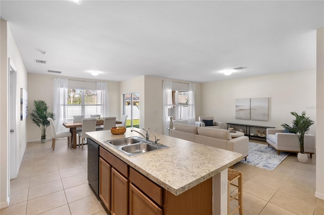 kitchen featuring dishwasher, sink, a center island with sink, and light tile patterned floors