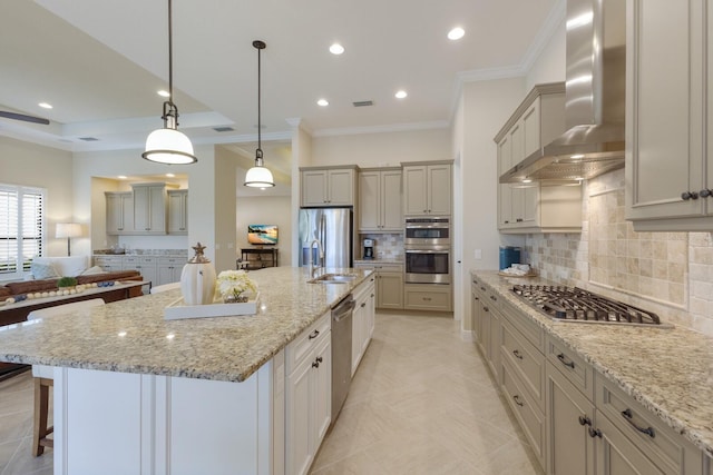 kitchen with appliances with stainless steel finishes, decorative light fixtures, light stone counters, wall chimney range hood, and a spacious island