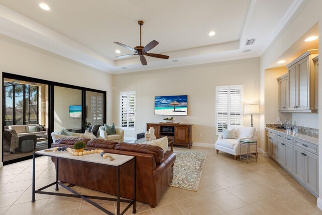 tiled living room featuring ceiling fan, plenty of natural light, and a tray ceiling