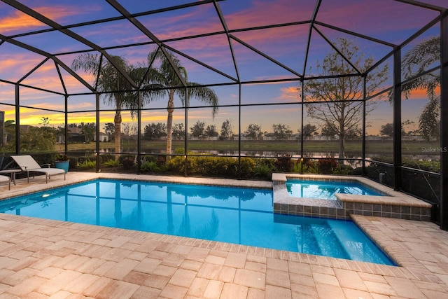 pool at dusk with an in ground hot tub, a patio, and glass enclosure