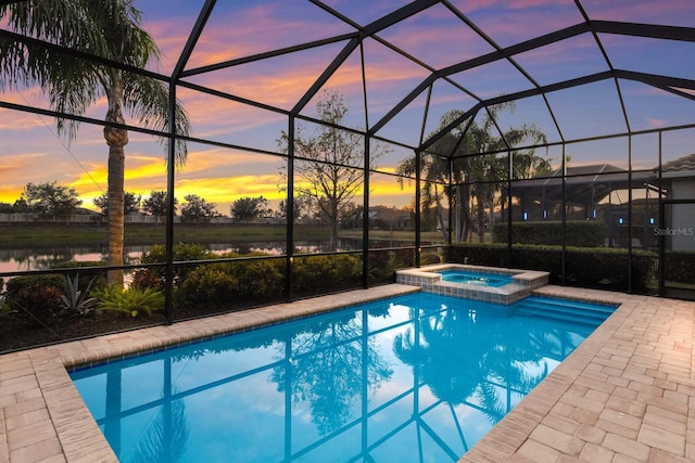 pool at dusk featuring a water view, an in ground hot tub, a lanai, and a patio