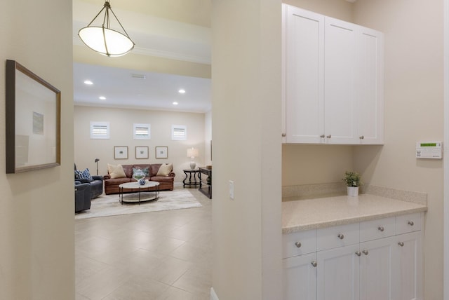 interior space with hanging light fixtures, light stone countertops, and white cabinets