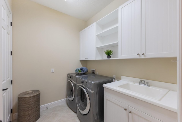 clothes washing area with cabinets, washing machine and dryer, sink, and light tile patterned flooring