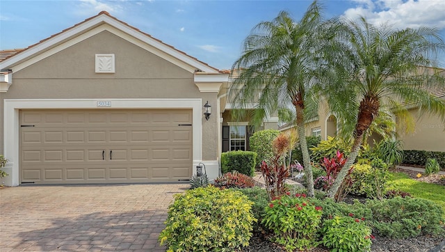 view of front facade with stucco siding, decorative driveway, and a garage