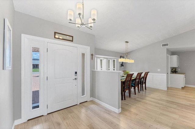 foyer featuring an inviting chandelier, a healthy amount of sunlight, and light hardwood / wood-style flooring