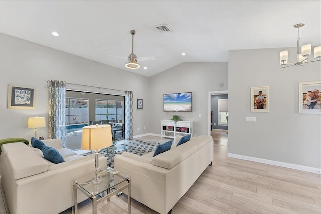 living area with visible vents, baseboards, vaulted ceiling, light wood-style flooring, and ceiling fan with notable chandelier