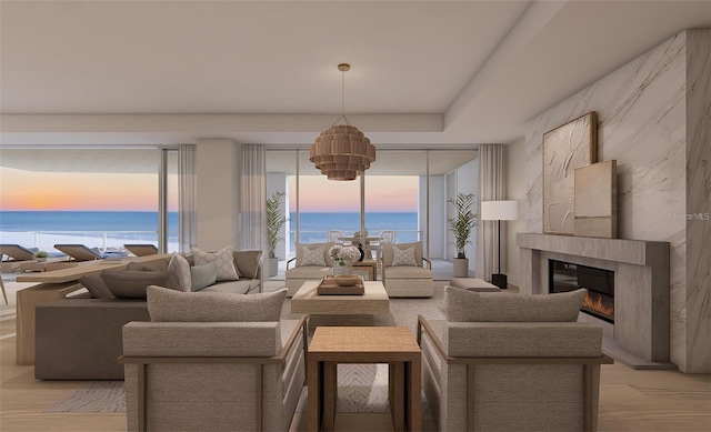 living room with a water view, a high end fireplace, and light hardwood / wood-style floors