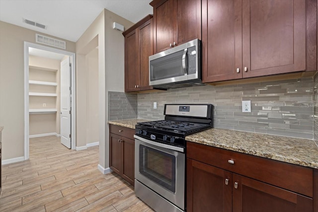 kitchen featuring light stone counters, backsplash, and appliances with stainless steel finishes