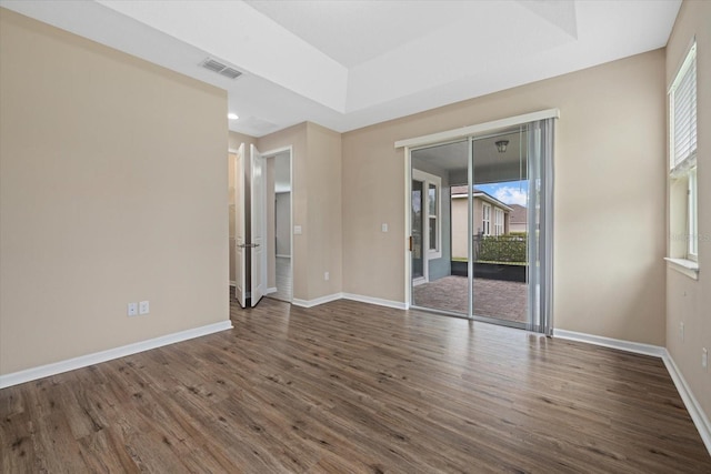 spare room featuring dark wood-type flooring and a raised ceiling