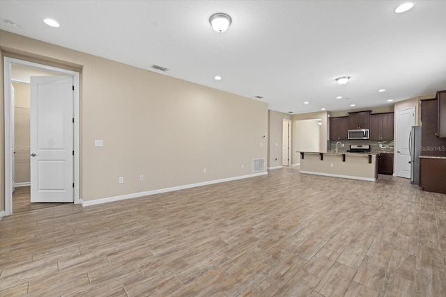 unfurnished living room with sink and light hardwood / wood-style flooring