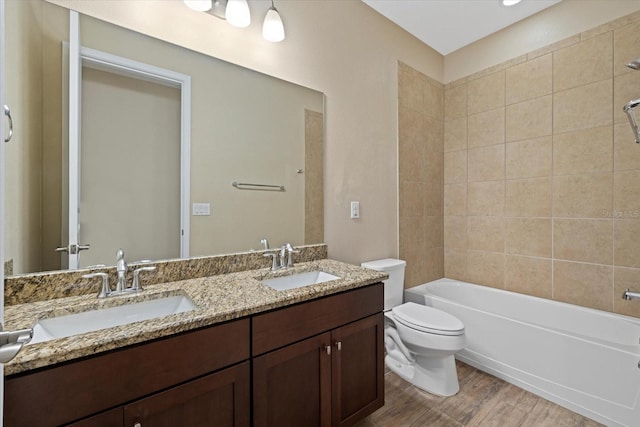 full bathroom featuring tiled shower / bath, vanity, and toilet