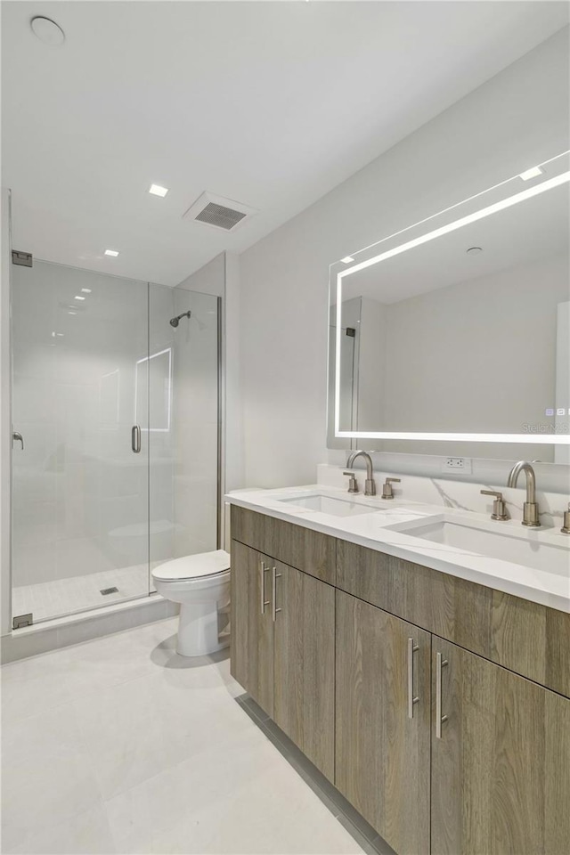 bathroom featuring vanity, a shower with shower door, and toilet