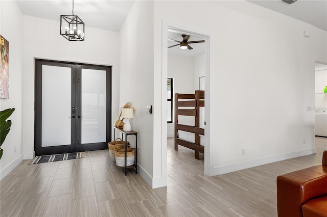 foyer with a notable chandelier, light wood-type flooring, and french doors