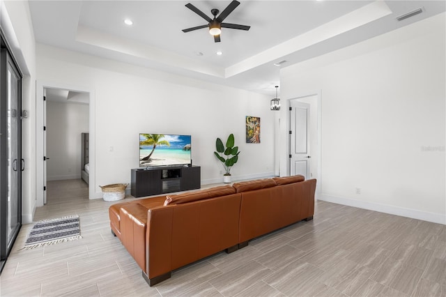 living room featuring a raised ceiling and ceiling fan