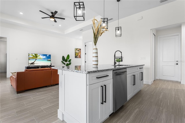 kitchen featuring sink, dishwasher, light stone countertops, a center island with sink, and decorative light fixtures