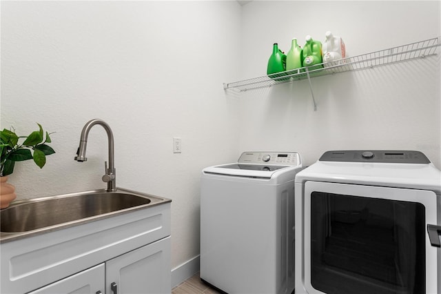 clothes washing area with cabinets, separate washer and dryer, and sink