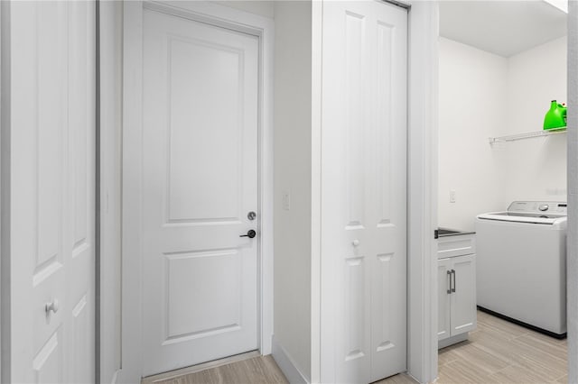 clothes washing area with washer / clothes dryer and light hardwood / wood-style flooring