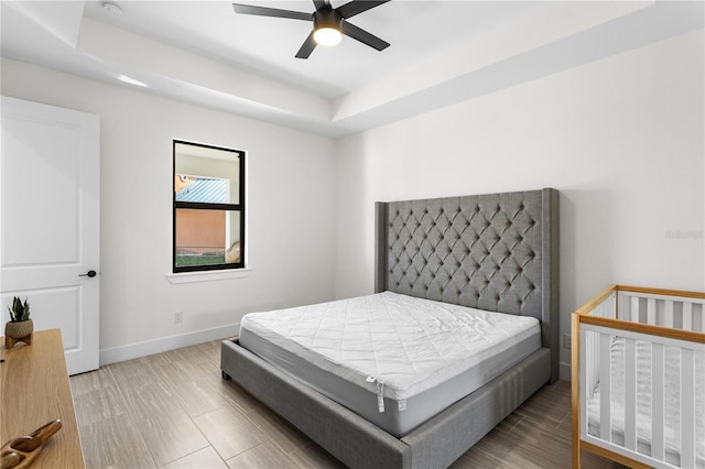 bedroom with ceiling fan and a raised ceiling