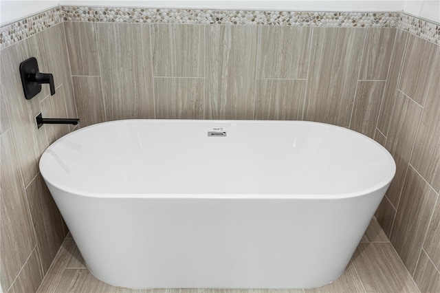 bathroom with tile patterned floors, tile walls, and a washtub