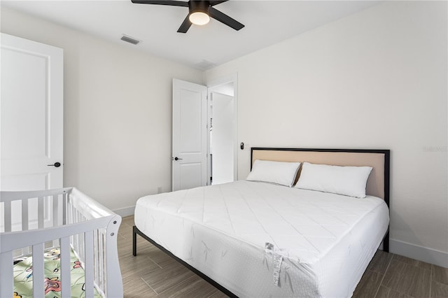 bedroom with dark hardwood / wood-style flooring and ceiling fan