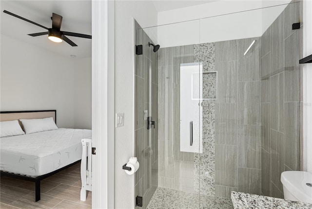 bathroom featuring ceiling fan, toilet, and a shower with shower door