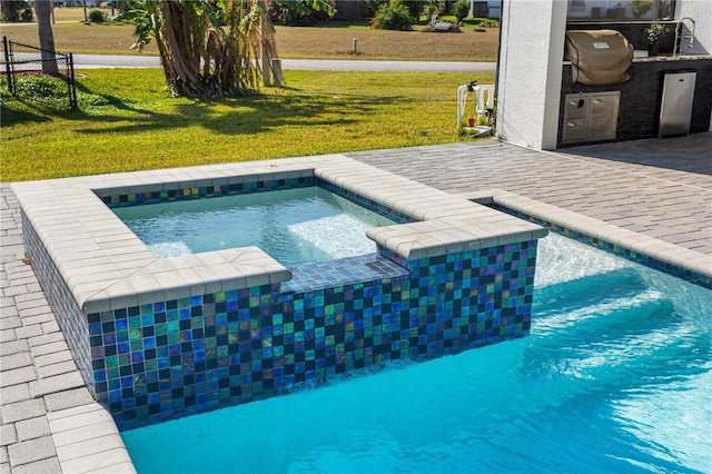 view of swimming pool featuring an outdoor kitchen, area for grilling, a lawn, an in ground hot tub, and a patio