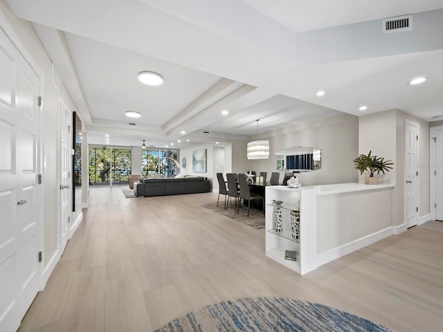 hallway featuring a raised ceiling and light wood-type flooring