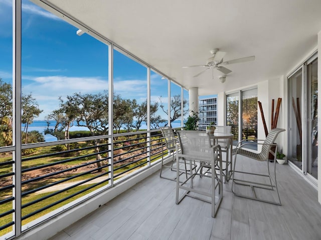 sunroom with ceiling fan, a healthy amount of sunlight, and a water view