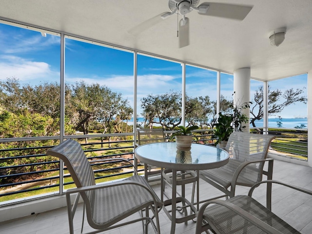 sunroom / solarium with ceiling fan and a water view