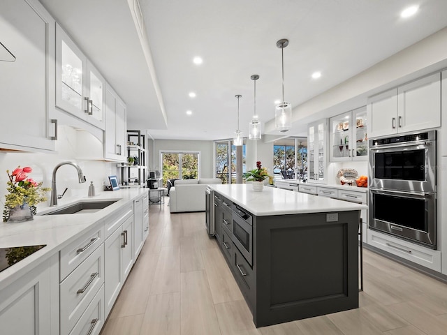 kitchen featuring sink, white cabinetry, a center island, hanging light fixtures, and appliances with stainless steel finishes