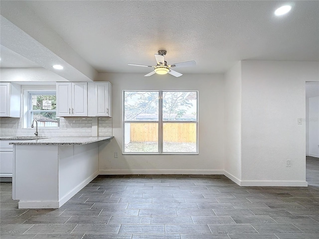 kitchen with white cabinetry, ceiling fan, light stone countertops, and tasteful backsplash