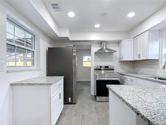 kitchen featuring wall chimney range hood, sink, appliances with stainless steel finishes, tasteful backsplash, and white cabinets