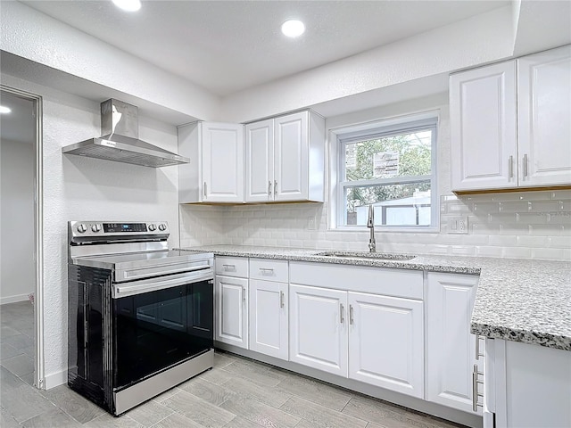 kitchen featuring wall chimney exhaust hood, sink, white cabinetry, stainless steel range with electric stovetop, and decorative backsplash