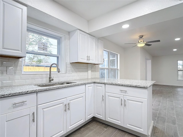 kitchen featuring sink, kitchen peninsula, white cabinets, and decorative backsplash