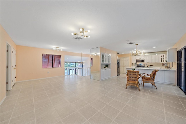 kitchen featuring pendant lighting, appliances with stainless steel finishes, an inviting chandelier, white cabinetry, and a kitchen breakfast bar