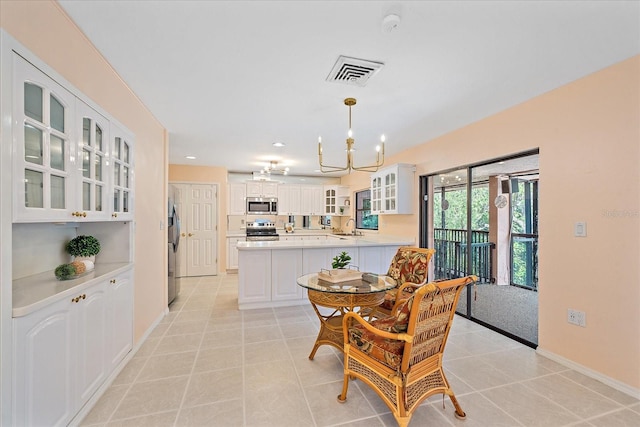 dining space featuring light tile patterned flooring, a chandelier, and sink