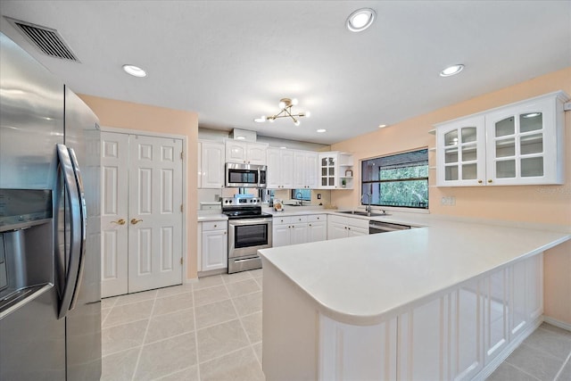 kitchen with stainless steel appliances, kitchen peninsula, and white cabinets