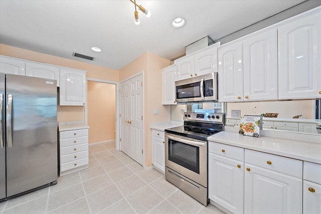 kitchen featuring light tile patterned flooring, appliances with stainless steel finishes, and white cabinets