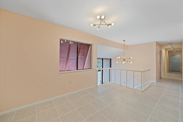 tiled spare room with a chandelier