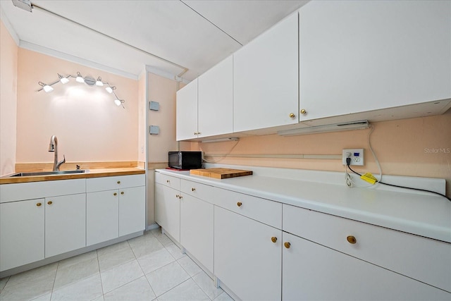 kitchen featuring white cabinetry, sink, and light tile patterned floors