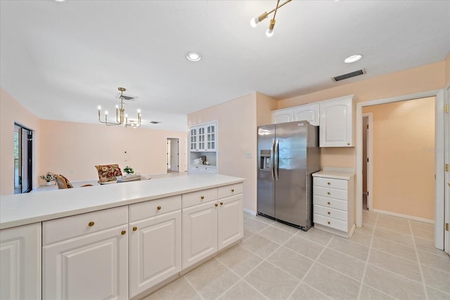 kitchen featuring white cabinetry, decorative light fixtures, light tile patterned floors, stainless steel fridge, and a notable chandelier