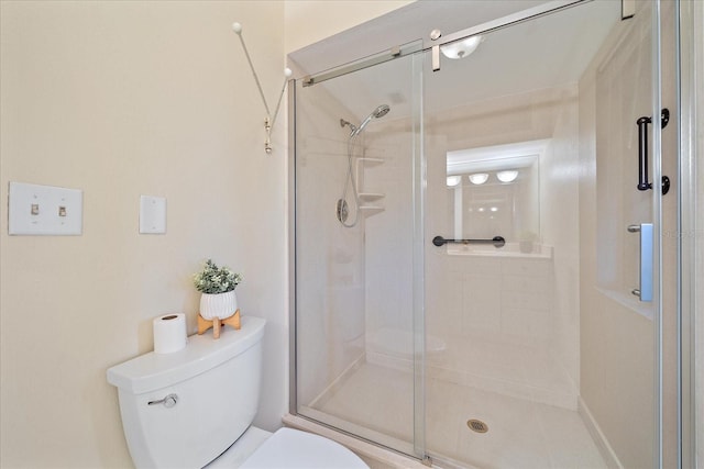 bathroom featuring a shower with door and toilet