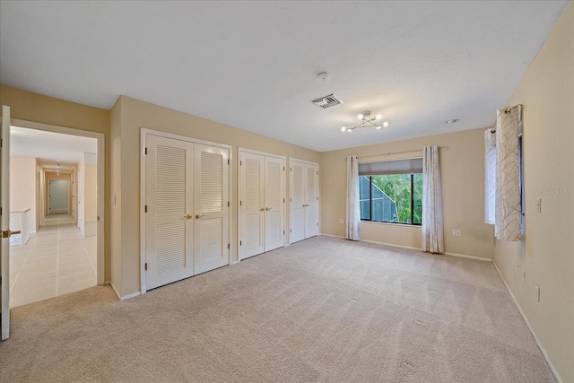 unfurnished bedroom featuring multiple closets and light carpet