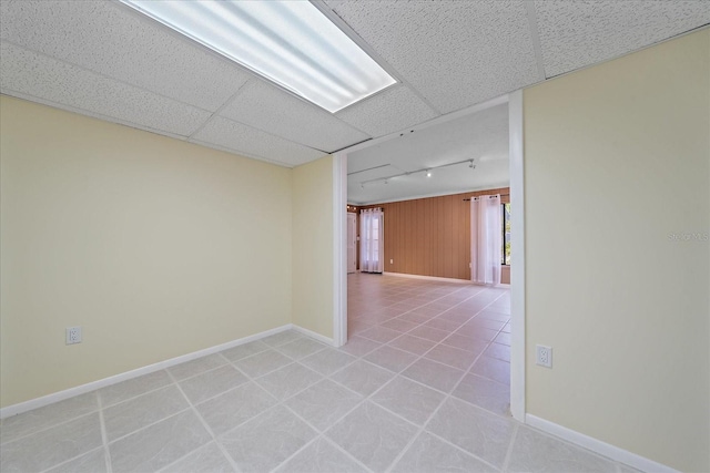 unfurnished room with track lighting, a drop ceiling, and light tile patterned floors