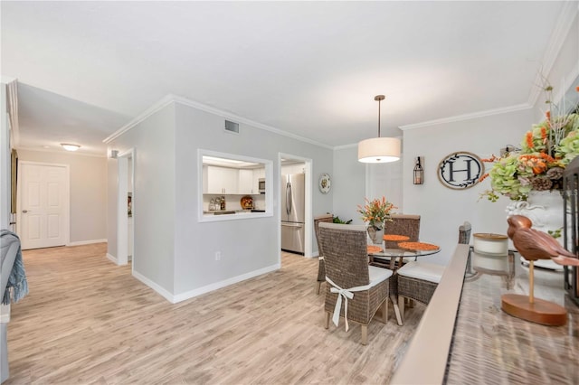 dining area with crown molding and light wood-type flooring