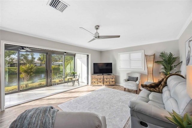 living room featuring wood-type flooring, ornamental molding, ceiling fan, and a water view