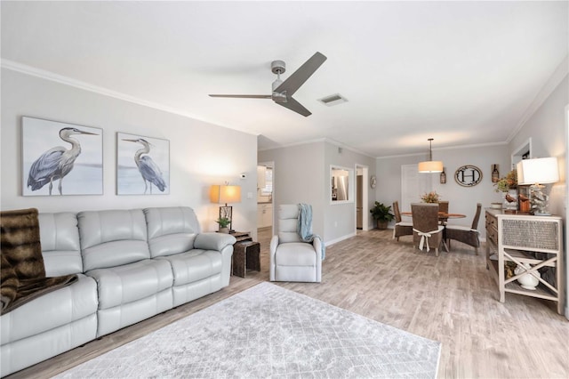 living room featuring ornamental molding, ceiling fan, and light wood-type flooring