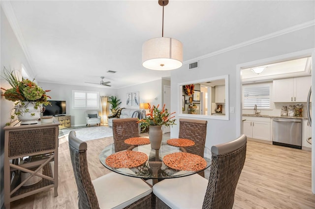 dining space with ceiling fan, ornamental molding, and light wood-type flooring