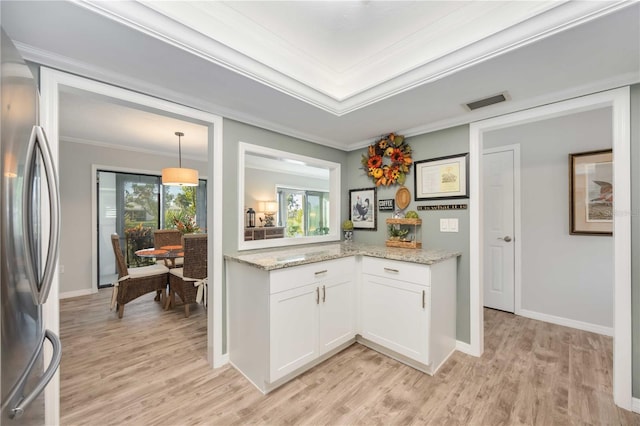 kitchen featuring light stone counters, light hardwood / wood-style flooring, ornamental molding, stainless steel fridge, and white cabinets